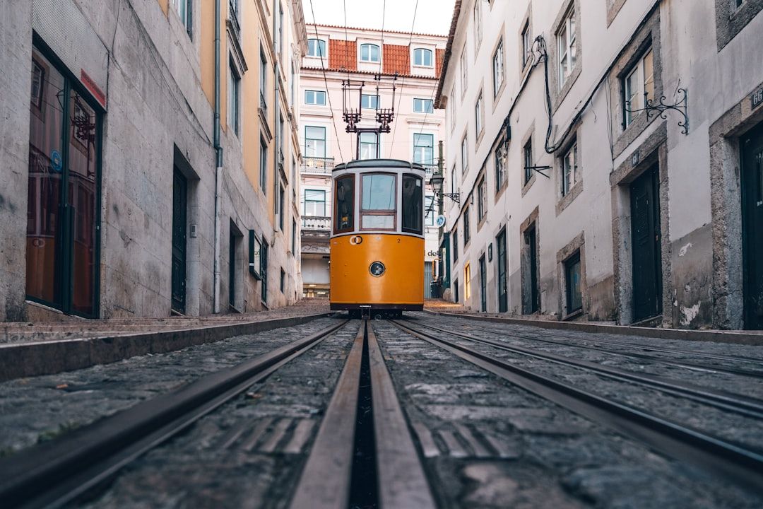 A yellow Lisbon tram climbing a narrow cobbled street