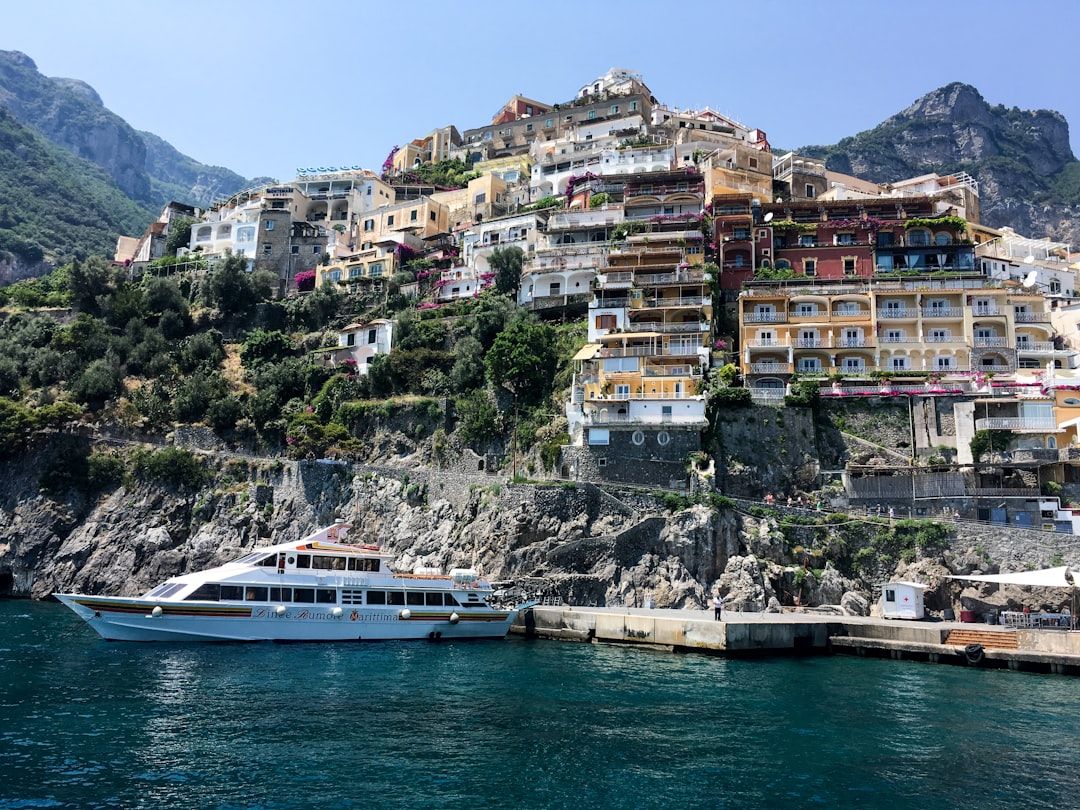 A passenger ferry approaching the Amalfi Coast with cliffside houses behind